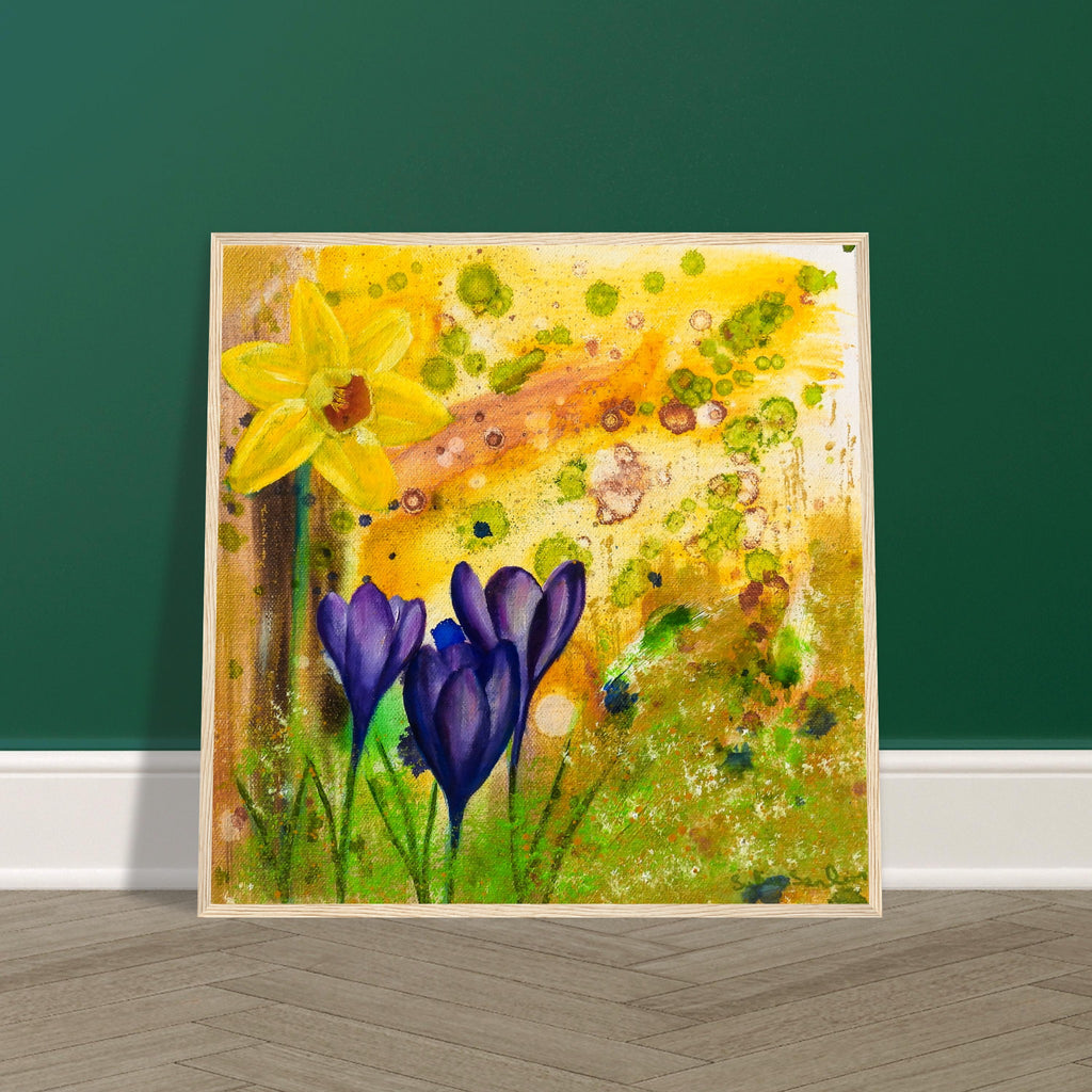 Spring flowers print framed in a natural wood frame propped against a dark green interior wall.