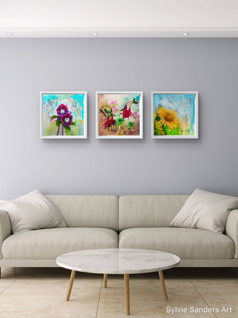 Three colorful abstract paintings on a gray wall above a beige sofa.